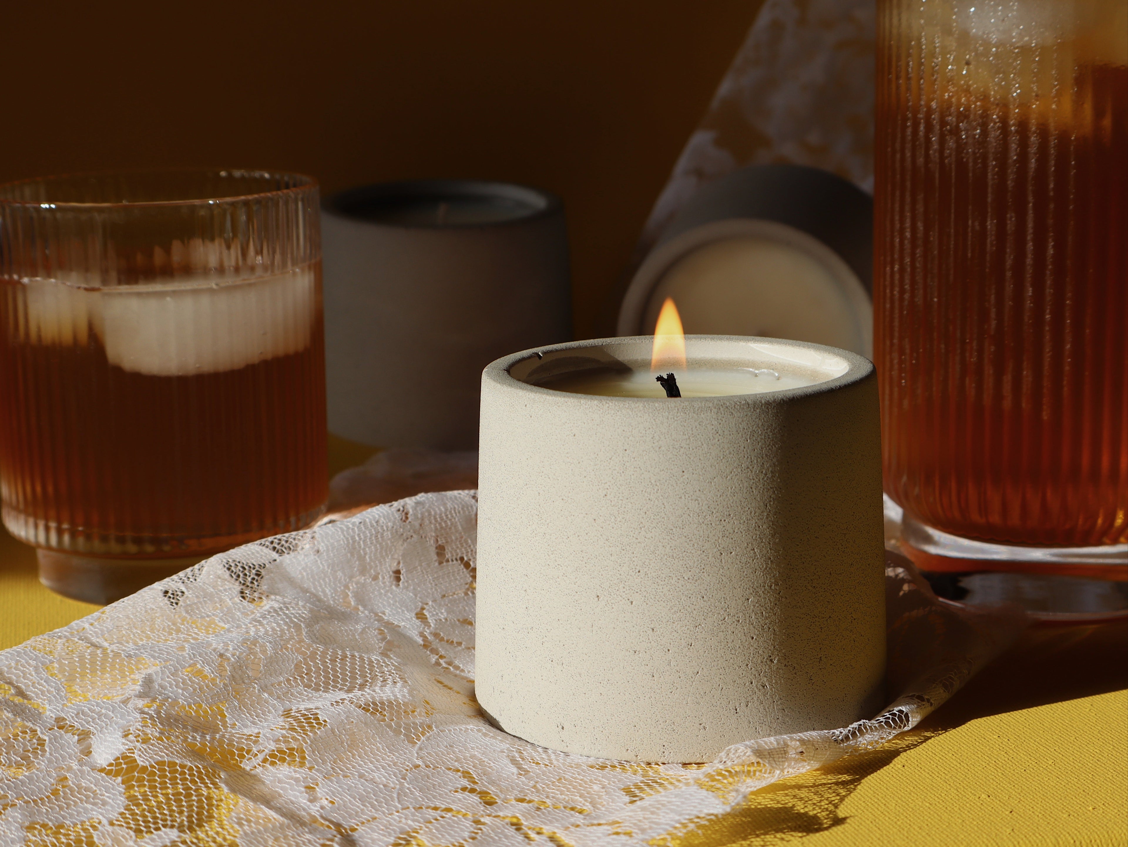 Candle and two glasses with a dark liquid on a lace tablecloth